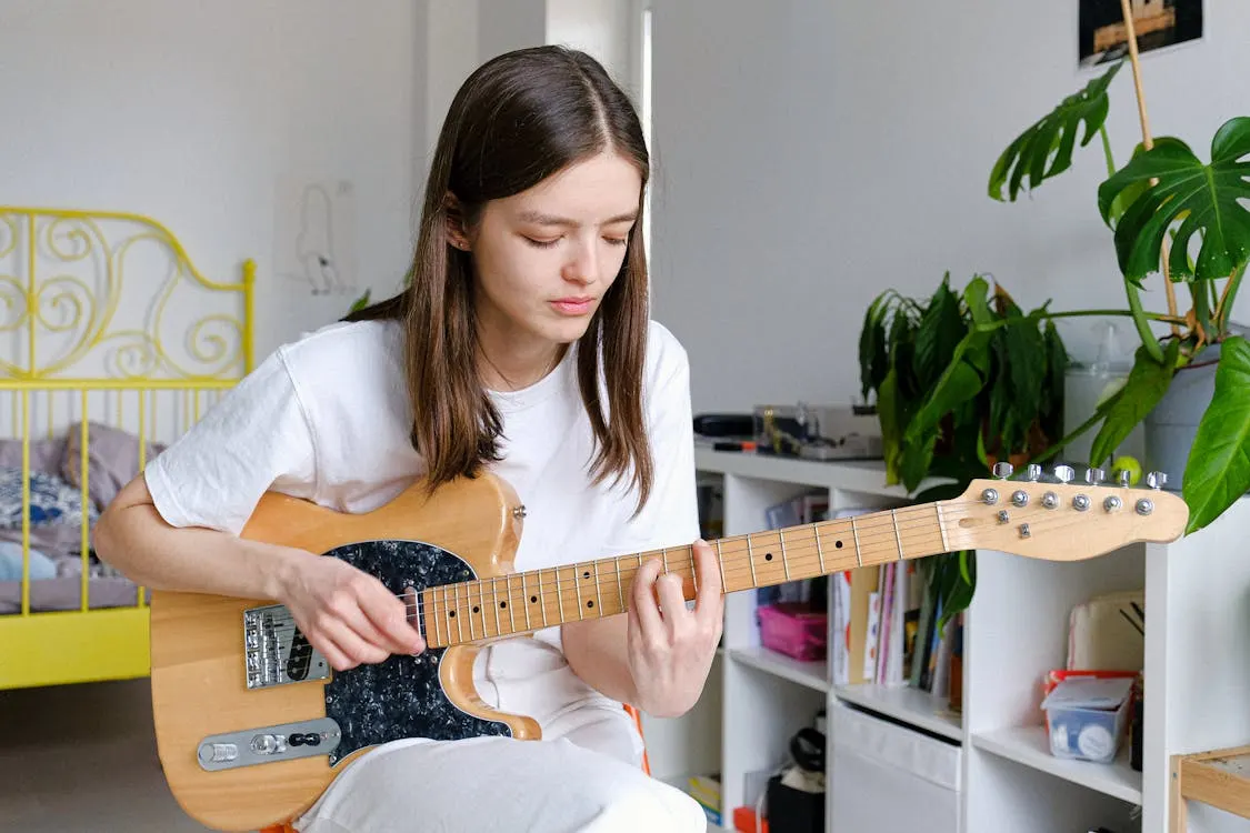 Woman In White Crew Neck T-shirt Playing Brown Electric Guitar