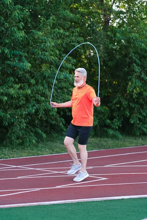 Senior sportsman training with jump rope on stadium